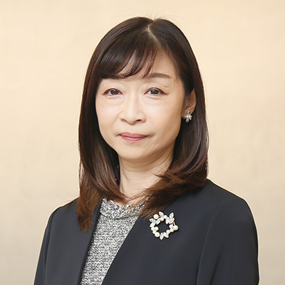 Takahashi is shown in a portrait against a neutral background. She is wearing a suit with a decorative brooch, presenting a professional appearance.